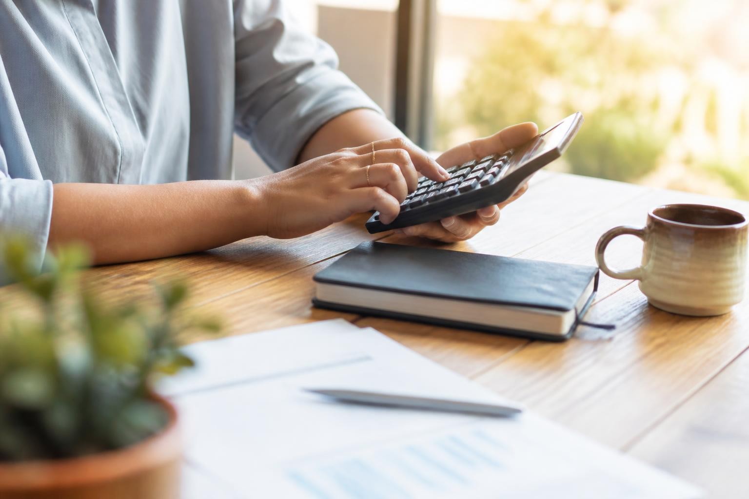 Calculadora e caderno sobre uma mesa, fazendo as contas do custo de divulgação