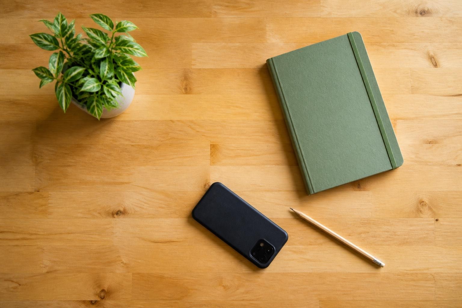 Mesa de trabalho com celular e caderno para planejar a arte de um post